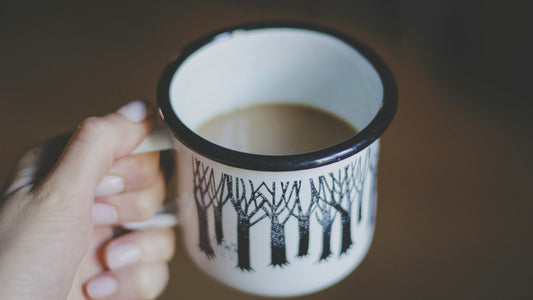 Hand holding a warm drink in a patterned white mug during a quiet evening routine