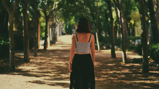 Woman walking away on a shaded tree-lined path