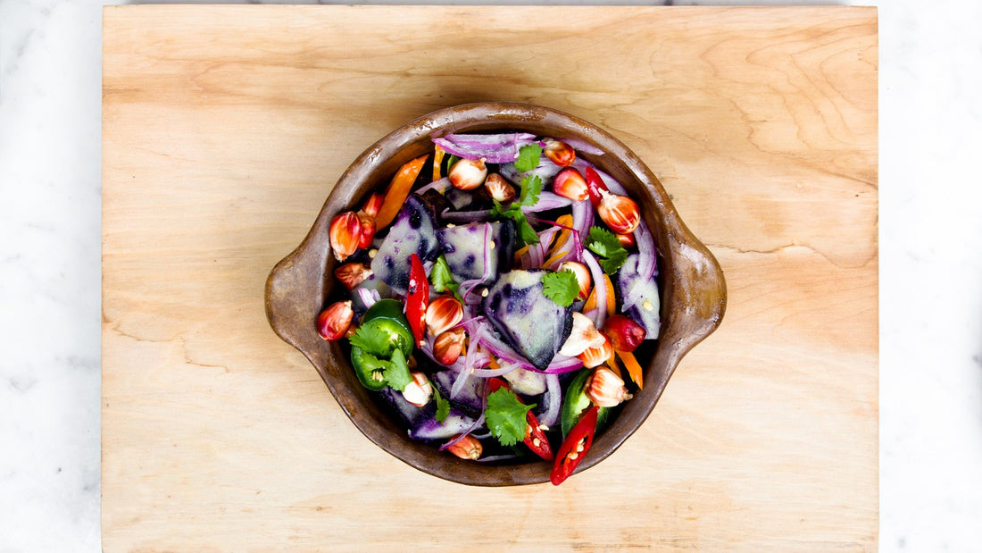 Colorful vegetable salad in a brown bowl on a light wooden cutting board