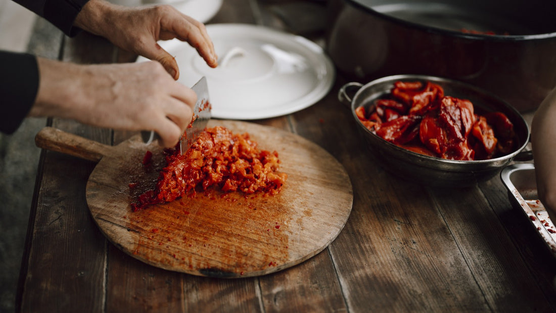 Hands chopping red vegetables on a wooden cutting board in a rustic kitchen